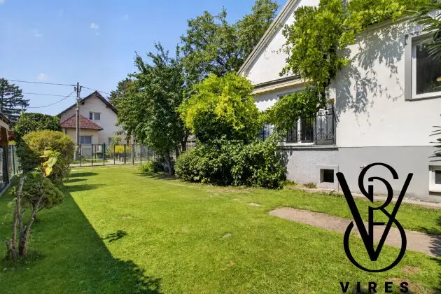 Garten mit Rasen und Glyzinie an der Hausecke